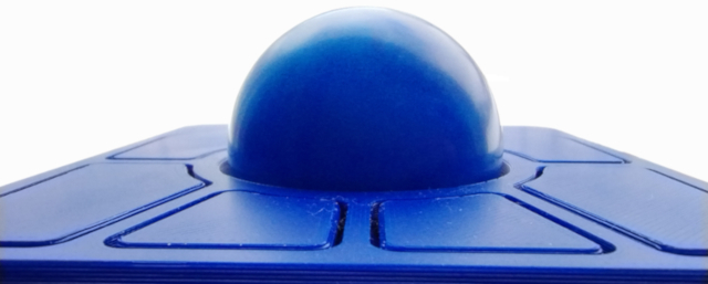 A macro shot of the blue Ploopy Adept against a white background showing the buttons across the bottom and the trackball looming over the scene taking up the middle section of the image